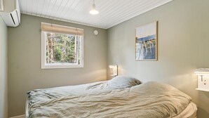 A bedroom with a bed, a window with a view of trees, a wall-mounted light, and a framed picture. - 4 bedroom nice home in Nexø (Nexø)