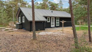 A small cabin with a sloped roof, a front porch, and a wooden deck. - 4 bedroom nice home in Nexø (Nexø)