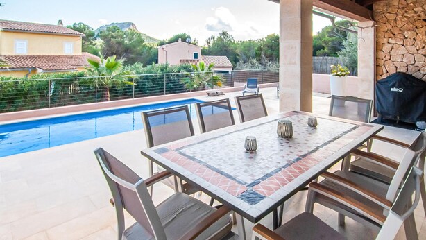 An outdoor patio with a pool, dining table, chairs, and a grill. - Beach front home in Mallorca (Mallorca)