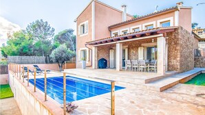 A two-story house with a stone exterior, a swimming pool, and a patio with outdoor furniture. - Beach front home in Mallorca (Mallorca)