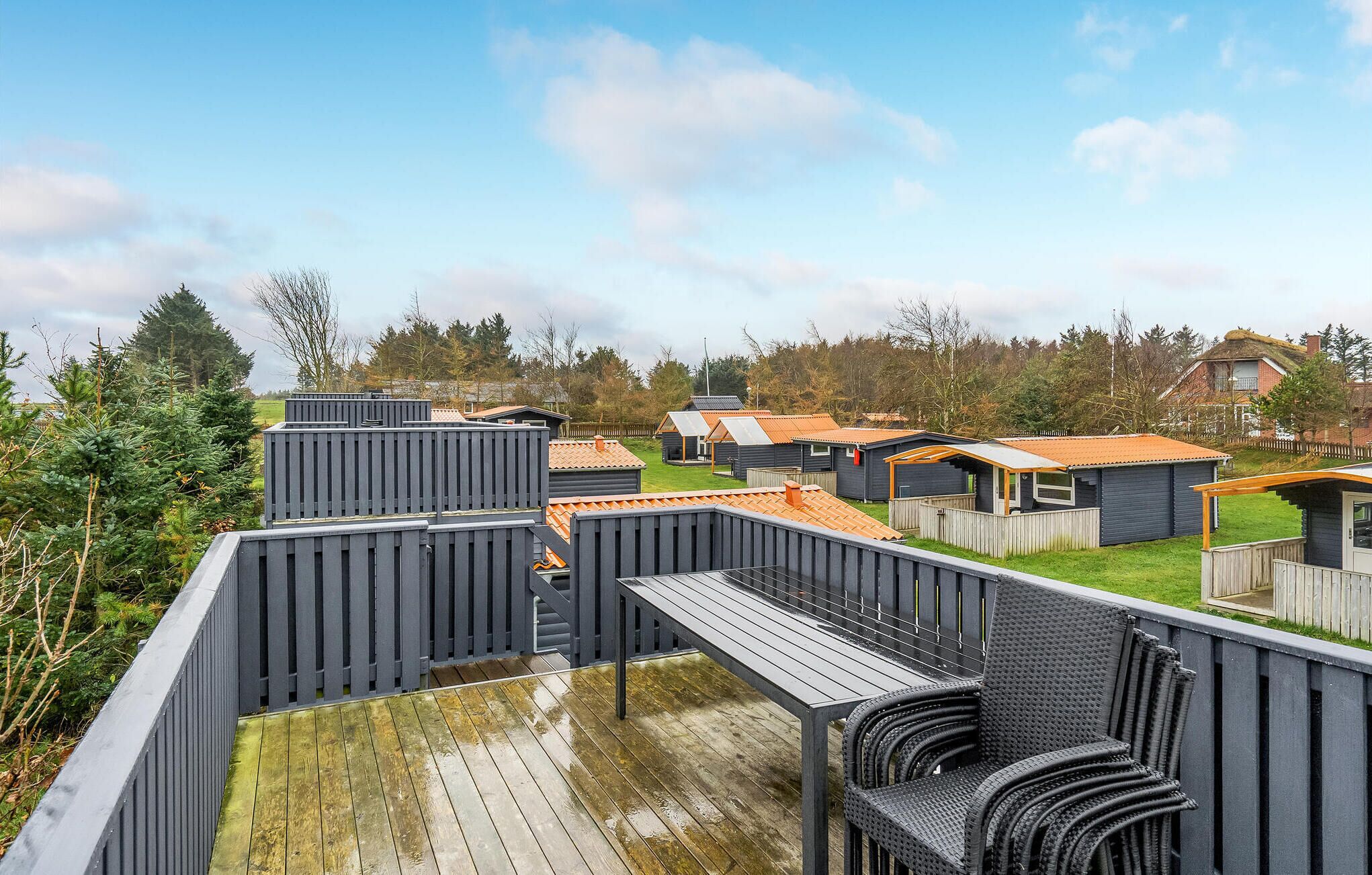 A view of a campsite with multiple cabins, a wooden deck, and surrounding greenery.