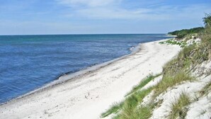 Een strand met wit zand en helderblauw water.