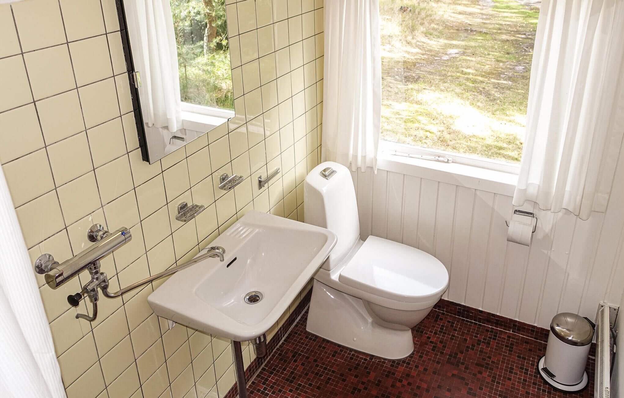 Et badeværelse med toilet, vask og vindue.