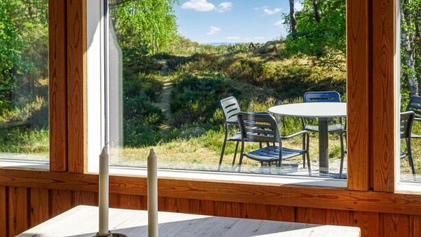 Een houten raamkozijn met uitzicht op een gazon, een tafel en twee stoelen.