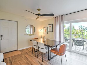Ein Essbereich mit Tisch, Stühlen, Deckenventilator, Spiegel und Blick ins Freie.