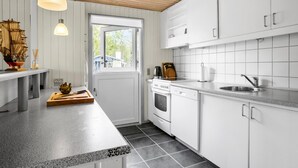 Una cocina moderna con armarios blancos, encimera de granito, horno empotrado y un fregadero.