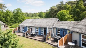 Une rangée de charmantes maisons bleues aux toits de tuiles, dotées de terrasses en bois et d’espaces aménagés pour se détendre en plein air.