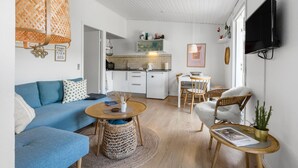 Un espace de vie compact comprenant un coin cuisine, un coin repas et un espace détente avec un canapé bleu et une petite table ronde.