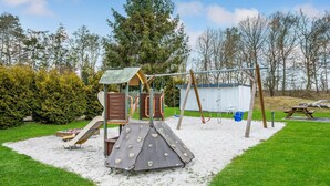Une aire de jeux avec un toboggan, une structure d’escalade et des balançoires.