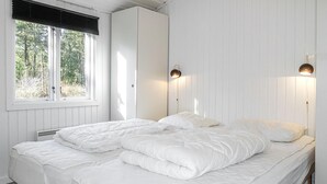 A bedroom with a bed, a wardrobe, and a window with blinds.