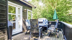 A wooden deck with outdoor furniture, including chairs and a table, and a green umbrella.