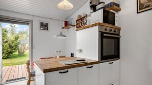 Kompakti keittiö, jossa on puinen työtaso, valkoiset kaapit ja sisäänrakennettu uuni.