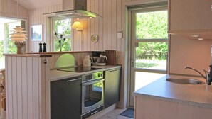 Une cuisine moderne équipée d’un four encastré, d’une machine à café et d’une fenêtre donnant sur la verdure environnante.