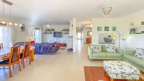A spacious living area with a dining table, sofa, and TV. - Beautiful villa with ocean & lagoon views,  walk to the beach! (Vau)