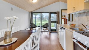 Eine kleine Küche mit Essbereich, Holzboden und großen Fenstern.
