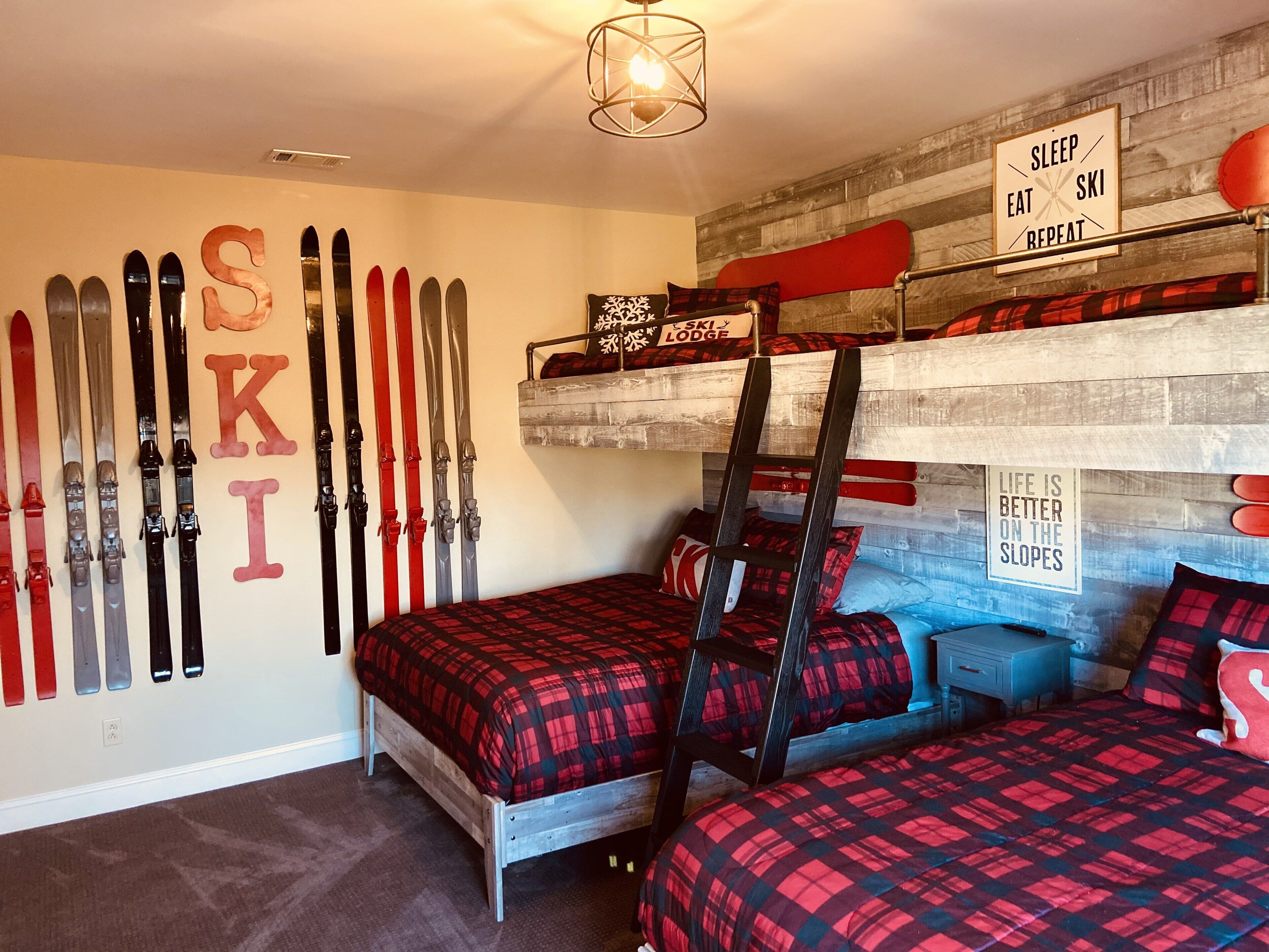 Een slaapkamer met een wintersportthema, met ski's bevestigd aan de muur, een stapelbed en aanmoedigende borden.
