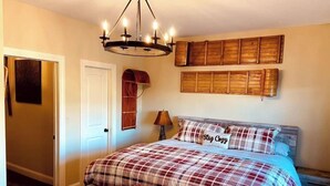 Ein Schlafzimmer mit Bett, einer Bank, einer Chandelüster und Holzbeschilderung an den Wänden.
