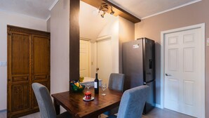 A dining area with a wooden table, four chairs, a refrigerator, and a door. - Stunning apartment in Kucice (Kucice)