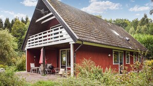 A red building with a sloped roof, a covered outdoor seating area, and a view of the surrounding forest. - 4 bedroom lovely home in Näsum (Näsum)