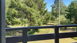 A view from a balcony with a railing, overlooking a grassy area with trees and a clear sky. - 4 bedroom lovely home in Näsum (Näsum)