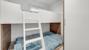 Un letto a castello con una scala, una testiera in legno e una finestra sopra il letto superiore.