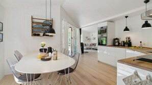 Een moderne keuken met witte kasten, een houten aanrechtblad en zwarte hanglampen.