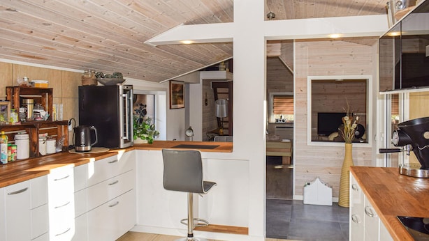 A modern kitchen with wooden cabinets, a black refrigerator, and a bar area with a stool. - Lovely home in Huskvarna (Huskvarna)