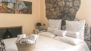 A neatly made bed with white linens, a bedside lamp, and a woven basket with towels. - Stunning home in Ficarra (Ficarra)