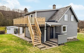 A two-story house with a wooden deck, a staircase, and a garage.