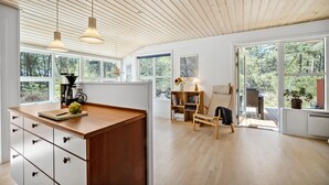 Een ruime kamer met grote ramen, een houten plafond en een centraal geplaatst eiland met lades.