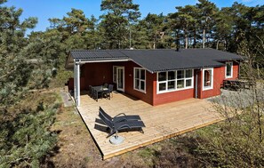 A small cabin with a deck, a table and chairs, and a patio umbrella. - 3 bedroom beautiful home in Aakirkeby (Aakirkeby)
