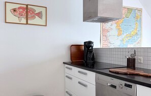 Una cocina con cafetera, un mapa y un cuadro de un pez enmarcado.