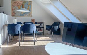 Un dormitorio tipo loft moderno con techo inclinado, un televisor de pantalla plana grande y una zona de comedor con un mapa en la pared.