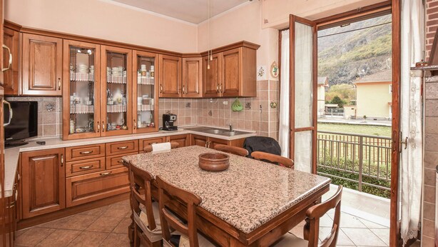 A kitchen with wooden cabinets, a granite countertop, and a dining area with chairs.