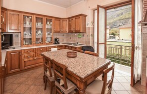 Eine Küche mit Holzausstattung, einer Arbeitsplatte aus Granit und einem Essbereich mit Stühlen.