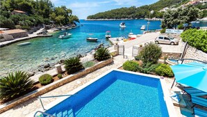 A swimming pool with clear blue water, surrounded by stone walls and greenery.