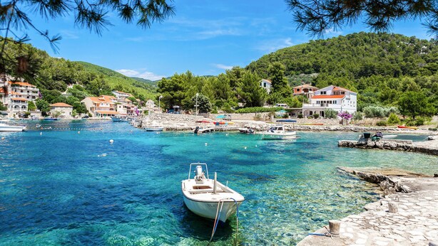 A coastal village with clear blue waters, boats, and traditional houses.