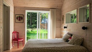 A bedroom with a bed, a red chair, a window, and a door. - 3 bedroom stunning home in Nexø (Nexø)