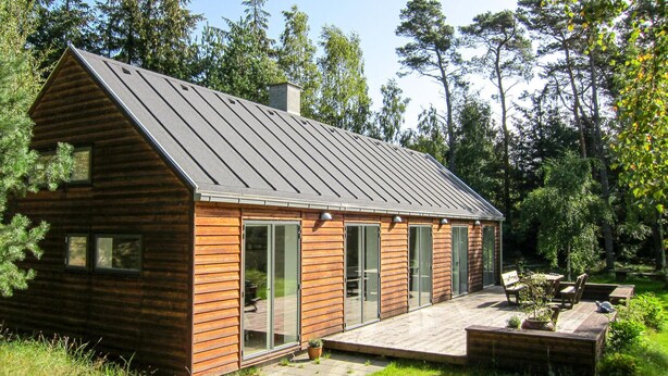 A cabin with a sloped roof, large windows, and a deck area with outdoor seating. - 3 bedroom stunning home in Nexø (Nexø)