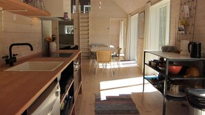 A modern kitchen with a wooden countertop, a sink, and a dining area with a table and chairs. - 3 bedroom stunning home in Nexø (Nexø)