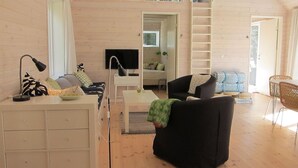 A spacious loft-style living area with a high ceiling, wooden walls, a sofa, a coffee table, a TV, and a ladder leading to an upper level. - 3 bedroom stunning home in Nexø (Nexø)