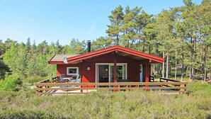 A red cabin with a deck, surrounded by trees. - Pet friendly home in Nexø with kitchen (Nexø)