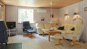A cozy living room with a TV, leather armchair, white sofa, and wooden coffee table. - Stunning home in Nexø with WiFi (Nexø)