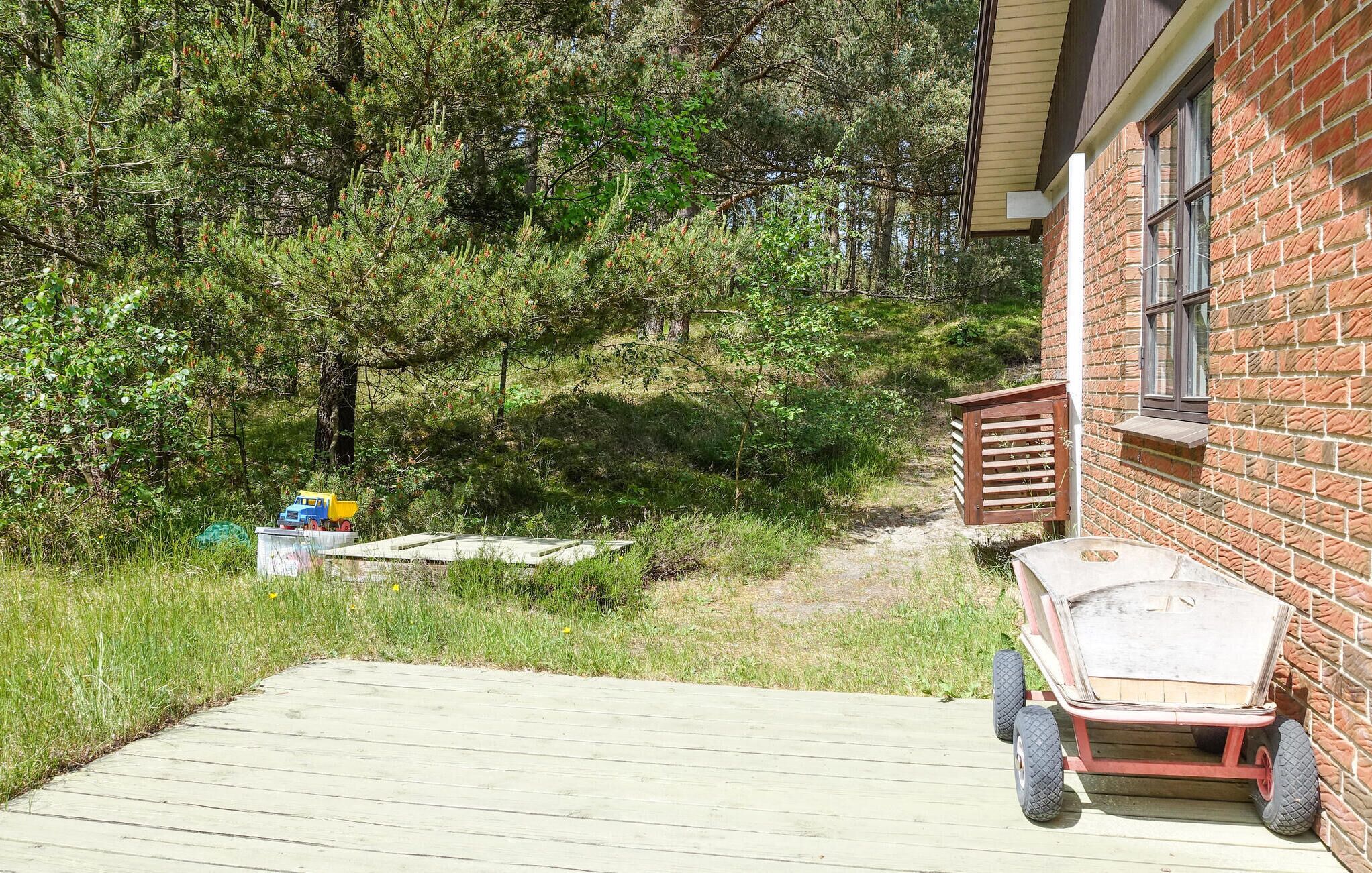 A wooden deck with a wheelbarrow and a small shed.