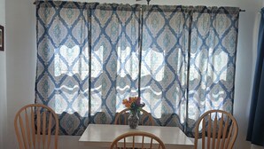 A dining area with a table and two wooden chairs, a ceiling fan, and patterned curtains. -  Cozy home in Wisconsin's recreational northwoods. (Butternut)