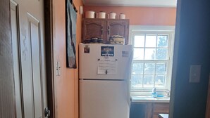 A kitchen with a white refrigerator, wooden cabinets, and a window with a view. -  Cozy home in Wisconsin's recreational northwoods. (Butternut)