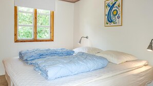Una camera da letto con un letto, una finestra, una lampada a parete e un quadro.