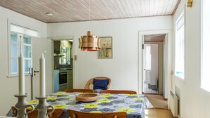 Zona pranzo con tavolo apparecchiato per quattro, lampada a sospensione in rame e vista sulla cucina.