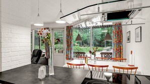 A modern kitchen with a black countertop, a built-in oven, and a dining area with wooden chairs and a table.
