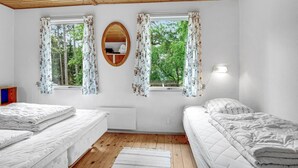 A bedroom with two beds, wooden flooring, and a ceiling with exposed beams.